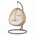 Fauteuil suspendu bohème en rotin tressé naturel avec support noir et coussins beiges, 105 x 105 x 195 cm